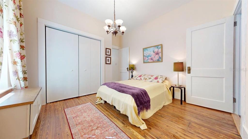 A bedroom features hardwood floors, a bed with yellow bedding, a closet, and a chandelier — 2010 S MAPLE AVENUE, SANFORD, FL