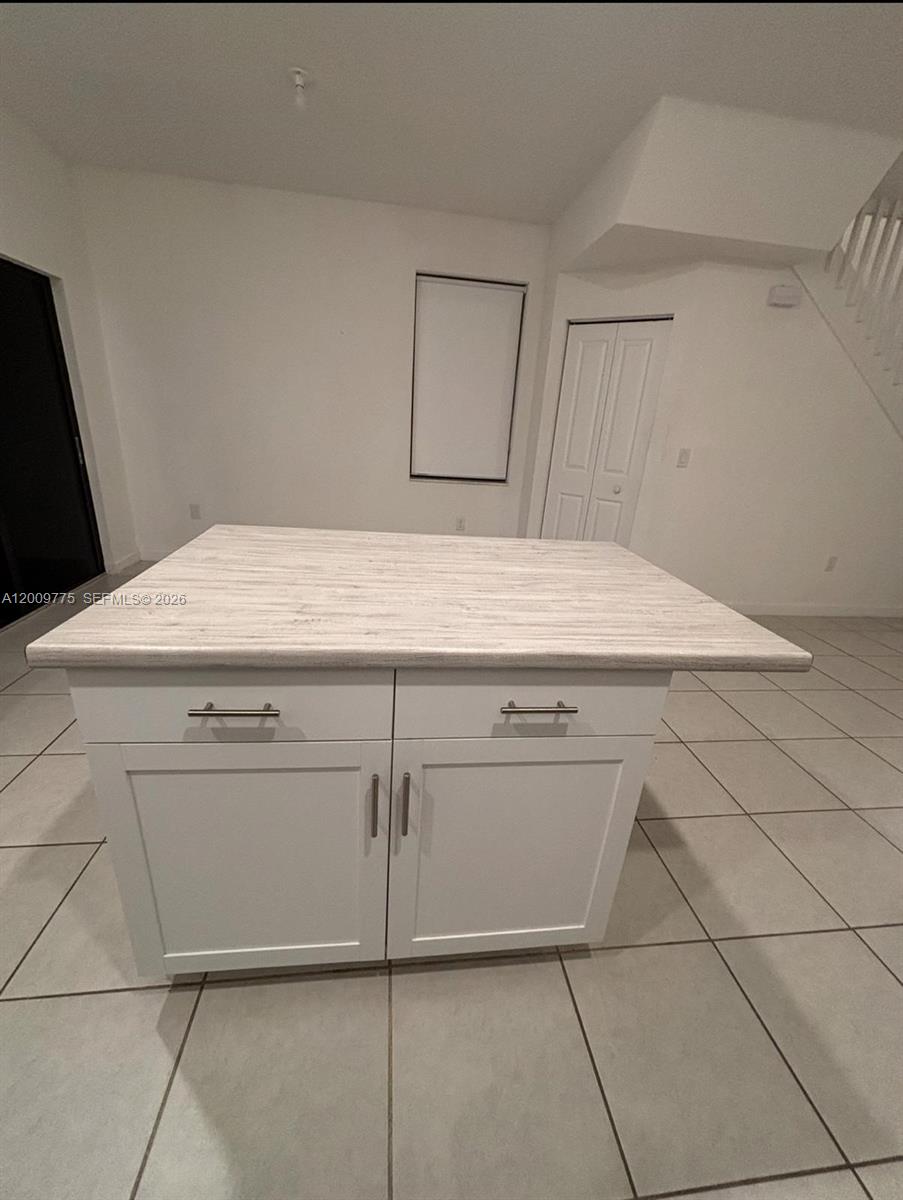 A kitchen island with a light wood-grain countertop and white cabinets sits on tiled flooring — 20964 NE 8th Ave, Miami FL 33179, MIAMI, FL