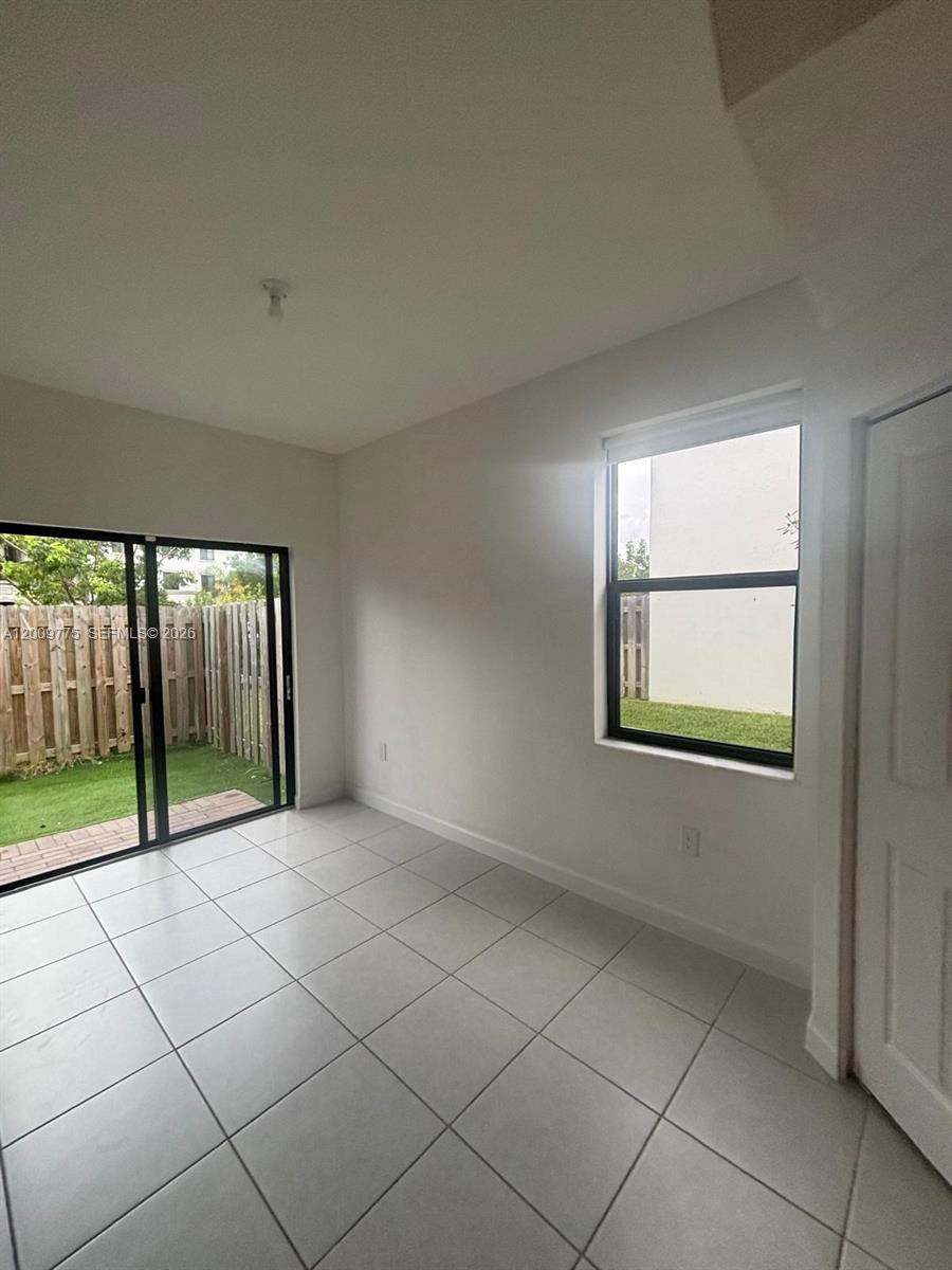 An empty room with white walls, tile flooring, a sliding glass door, and a window — 20964 NE 8th Ave, Miami FL 33179, MIAMI, FL