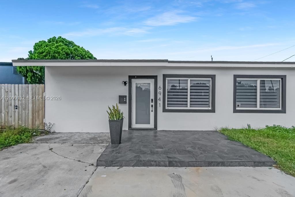 The exterior of a single-story house features a tiled front porch and a glass-paneled door — 6941 Sheridan St, Hollywood FL 33024, HOLLYWOOD, FL