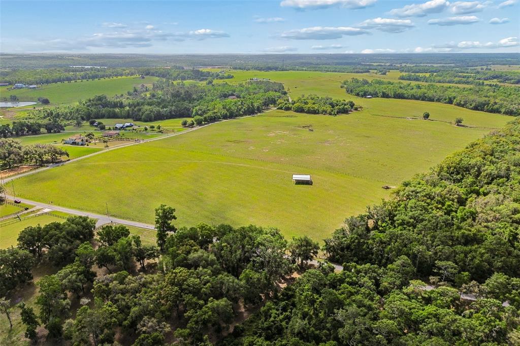 An aerial view shows a large, open green pasture surrounded by trees and rural roads — BAYHEAD ROAD Lot 9, DADE CITY, FL