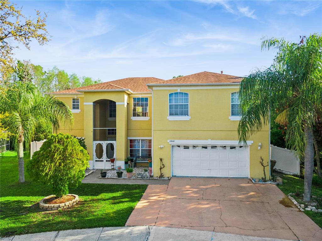 A dining area with a wooden table and chairs sits before an open kitchen — 2606 ROYAL FERN PLACE, KISSIMMEE, FL