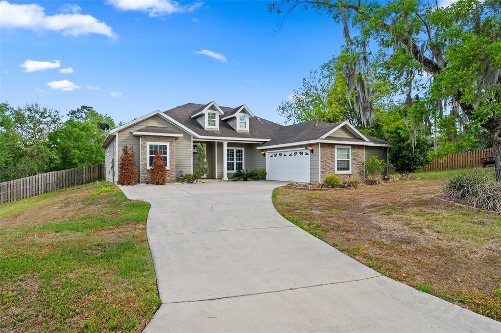 A single-story house with a concrete driveway, stone accents, and two dormer windows — 14825 NW 151ST LANE, ALACHUA, FL