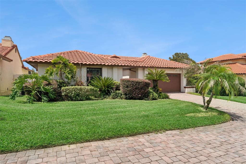 A single-story house with a terracotta tile roof, a paved driveway, and landscaped front yard — 7808 THE ESPLANADE COURT, ORLANDO, FL