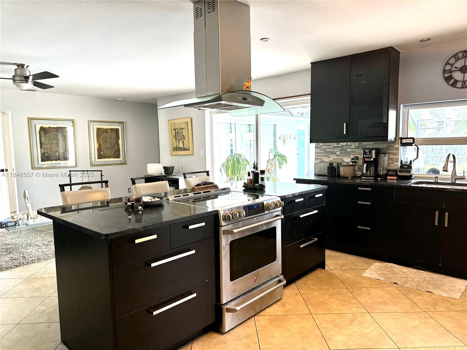 A kitchen features a central island with a stainless steel range and dark cabinetry — 4116 Taft St, Hollywood FL 33021, HOLLYWOOD, FL
