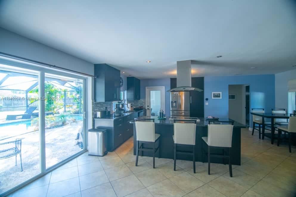 A kitchen with dark cabinetry, a central island with bar stools, and sliding glass doors — 4116 Taft St, Hollywood FL 33021, HOLLYWOOD, FL