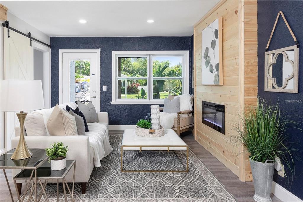 A living room features navy blue textured walls, a wood-paneled fireplace, and a white sofa — 4629 26TH AVENUE S, ST PETERSBURG, FL