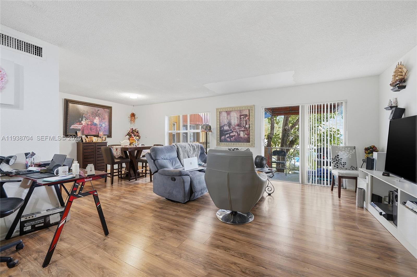 A living room features wood-look flooring, a dining area, and a sliding glass door — 17901 NW 68th Ave # R206, Hialeah FL 33015, HIALEAH, FL