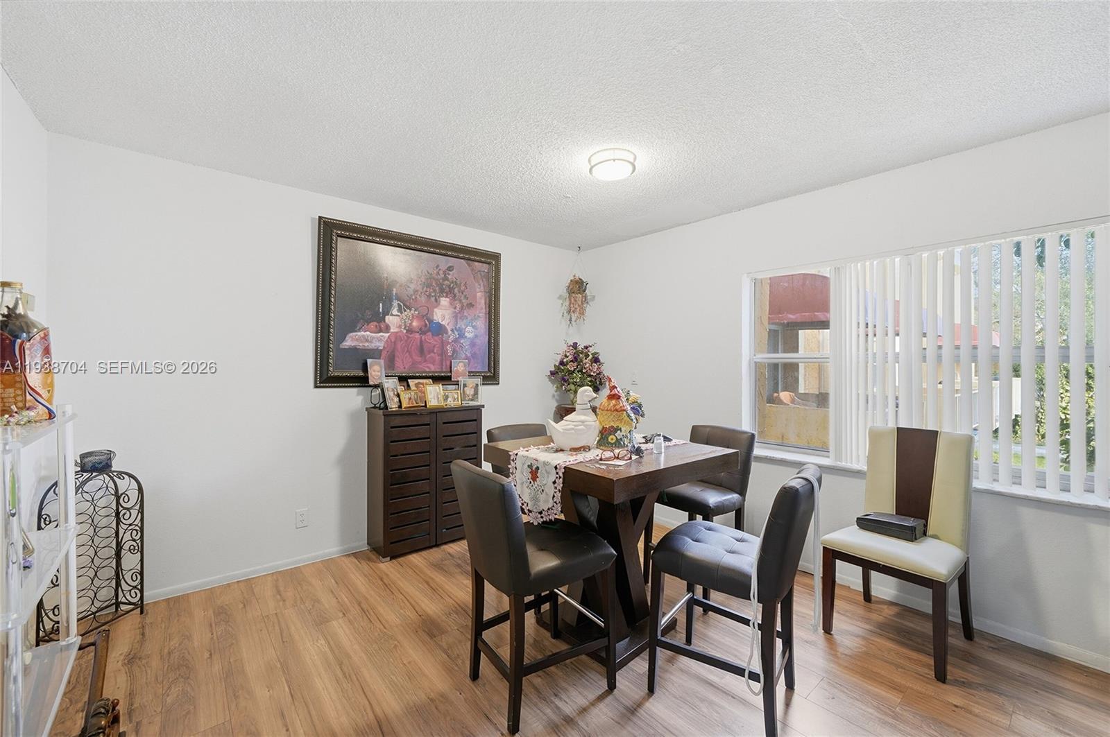 A dining room features wood-look flooring, a square table with four chairs, and wall art — 17901 NW 68th Ave # R206, Hialeah FL 33015, HIALEAH, FL