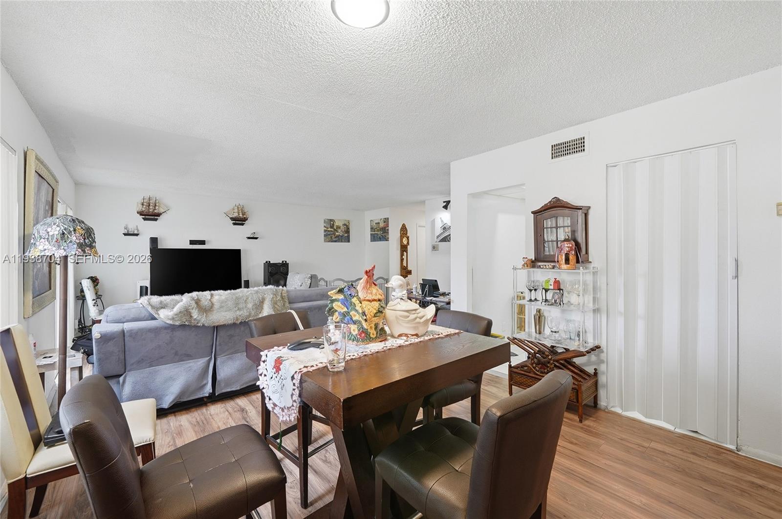 A dining area with a wooden table and chairs sits in front of a living room — 17901 NW 68th Ave # R206, Hialeah FL 33015, HIALEAH, FL