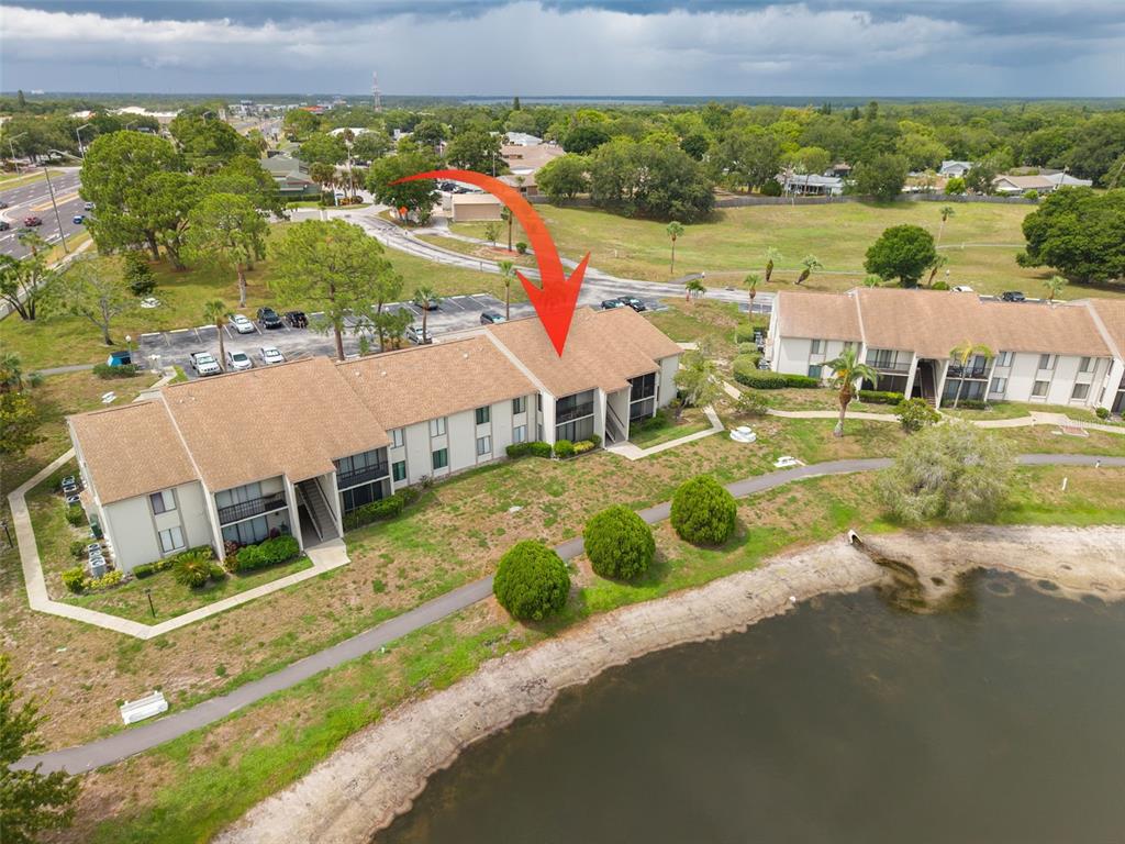 An aerial view shows a multi-unit residential building with a red arrow pointing to it — 1882 PINE RIDGE WAY W UNIT C2, PALM HARBOR, FL