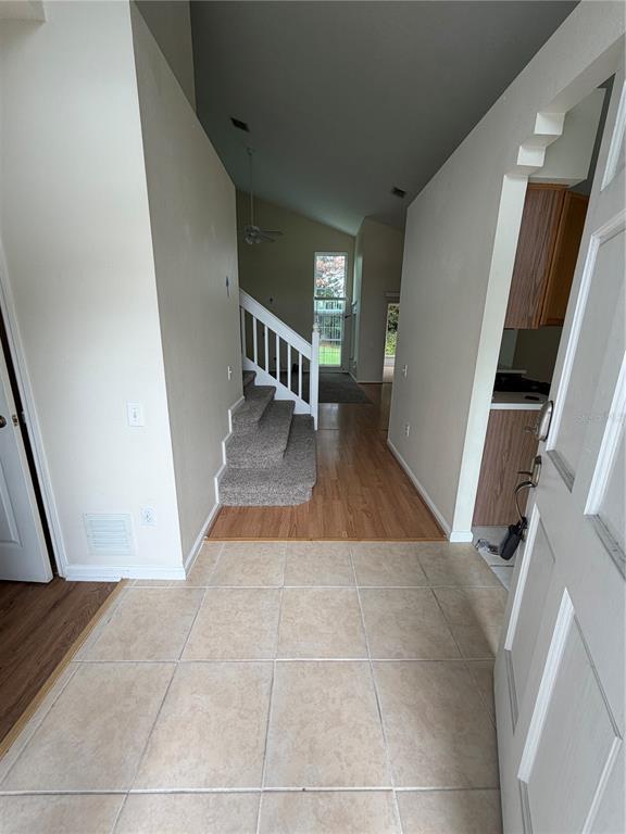 An entryway with tile flooring leads to a carpeted staircase and wood-floored living area — 3419 SANTA MONICA DRIVE, ORLANDO, FL