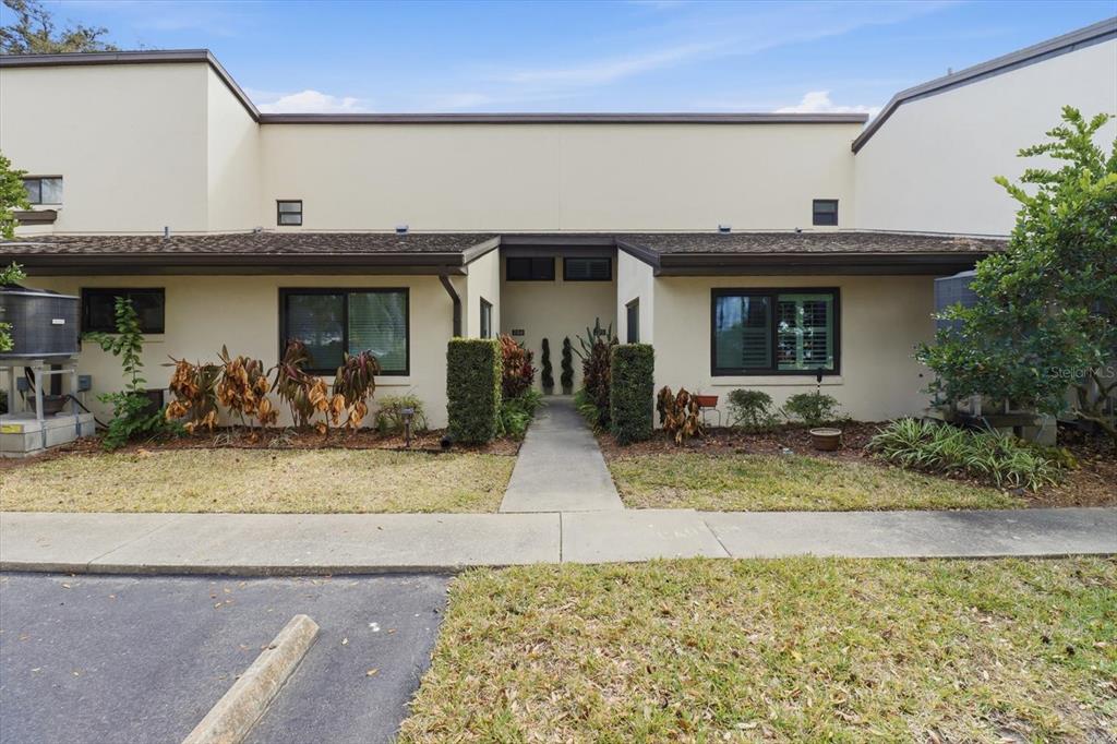 The exterior of a two-story townhouse features a concrete walkway leading to a central entrance — 1637 SE PARADISE CIRCLE UNIT 204, CRYSTAL RIVER, FL