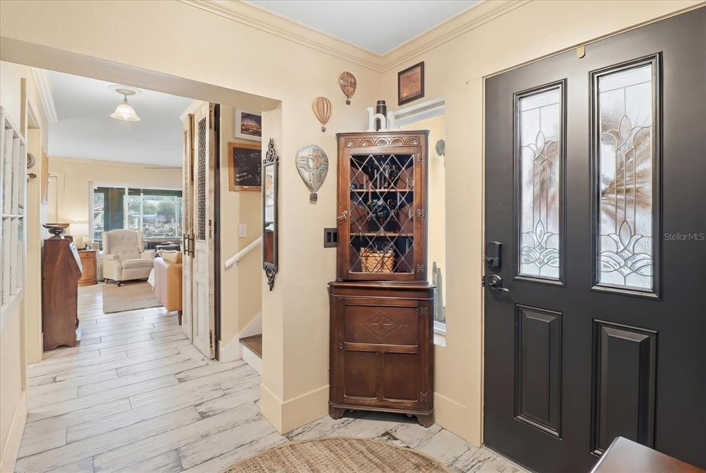 An entryway features a dark front door, a wooden corner cabinet, and light-colored wood flooring — 1637 SE PARADISE CIRCLE UNIT 204, CRYSTAL RIVER, FL