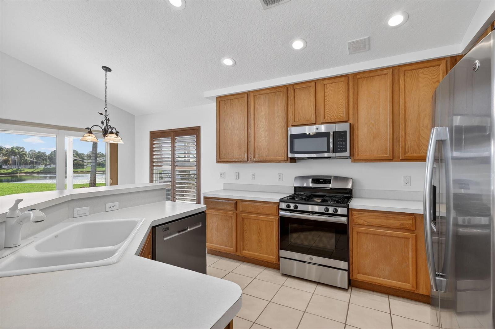 A kitchen features oak cabinets, stainless steel appliances, white countertops, and a view of water — 1021 SE Westminster Place, Stuart FL 34997, STUART, FL