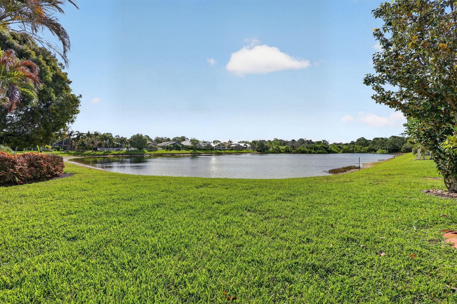 A grassy lawn leads to a lake with houses visible along the distant shore — 1021 SE Westminster Place, Stuart FL 34997, STUART, FL