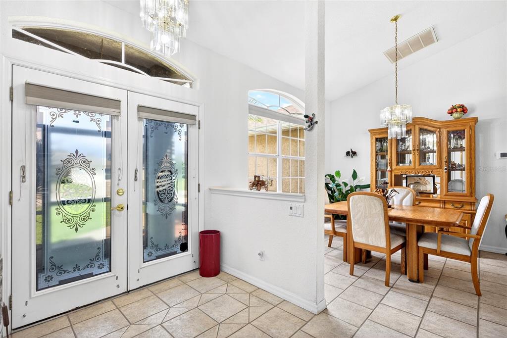 A dining area with a wooden hutch and table sits beside a tiled entryway — 4841 CAMELOT STREET, NORTH PORT, FL