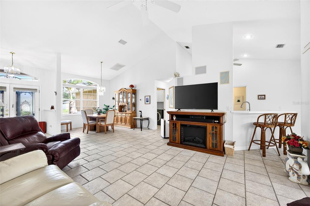 A spacious living room features tile flooring, a fireplace console, and an adjacent dining area — 4841 CAMELOT STREET, NORTH PORT, FL