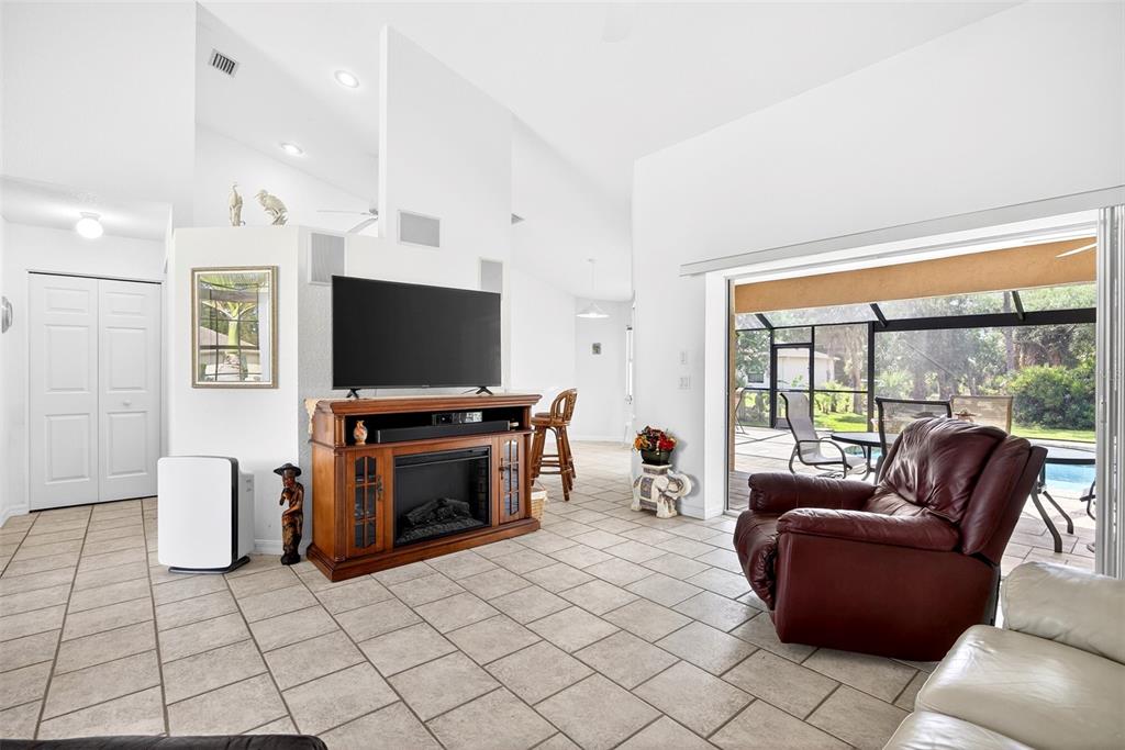 A living room with tile floors, a fireplace media console, and sliding doors to a patio — 4841 CAMELOT STREET, NORTH PORT, FL
