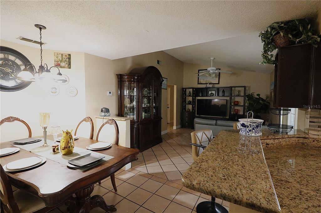 A dining area with a wooden table and hutch opens into a living room — 1419 CARRIAGE OAK COURT, OCOEE, FL