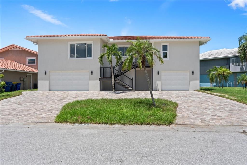 A two-story house with a paved driveway, two garage doors, and a central exterior staircase — 5151 PORPOISE PLACE, NEW PORT RICHEY, FL