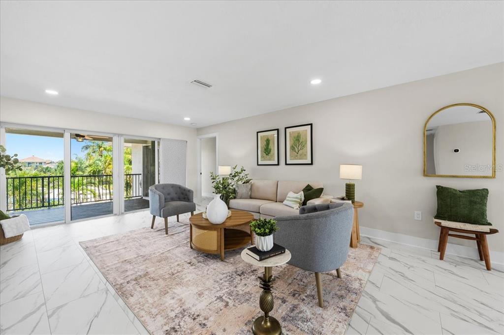 A bright living room features white marble-look tile floors, a beige sofa, and a balcony — 5151 PORPOISE PLACE, NEW PORT RICHEY, FL