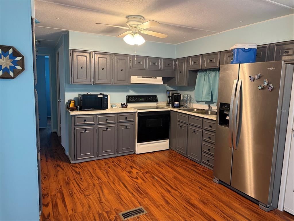 A kitchen features grey cabinets, stainless steel appliances, and wood-look flooring — 7411 FAIRLANE AVENUE, BROOKSVILLE, FL