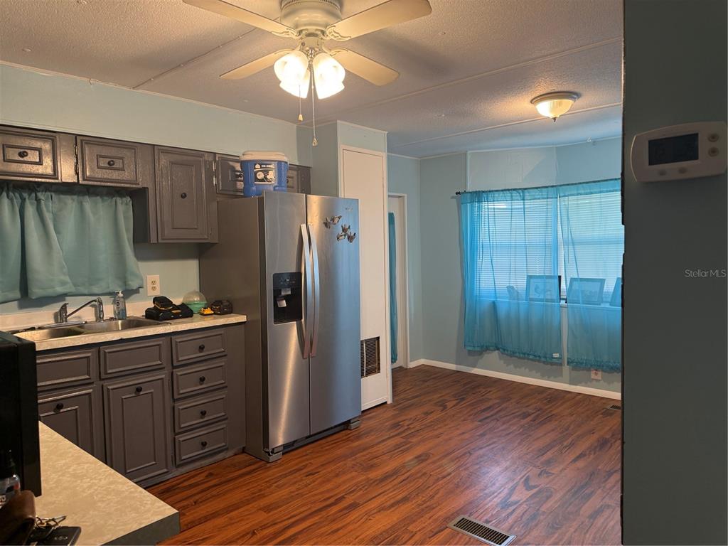 A kitchen with grey cabinets, stainless steel appliances, and wood-look flooring — 7411 FAIRLANE AVENUE, BROOKSVILLE, FL