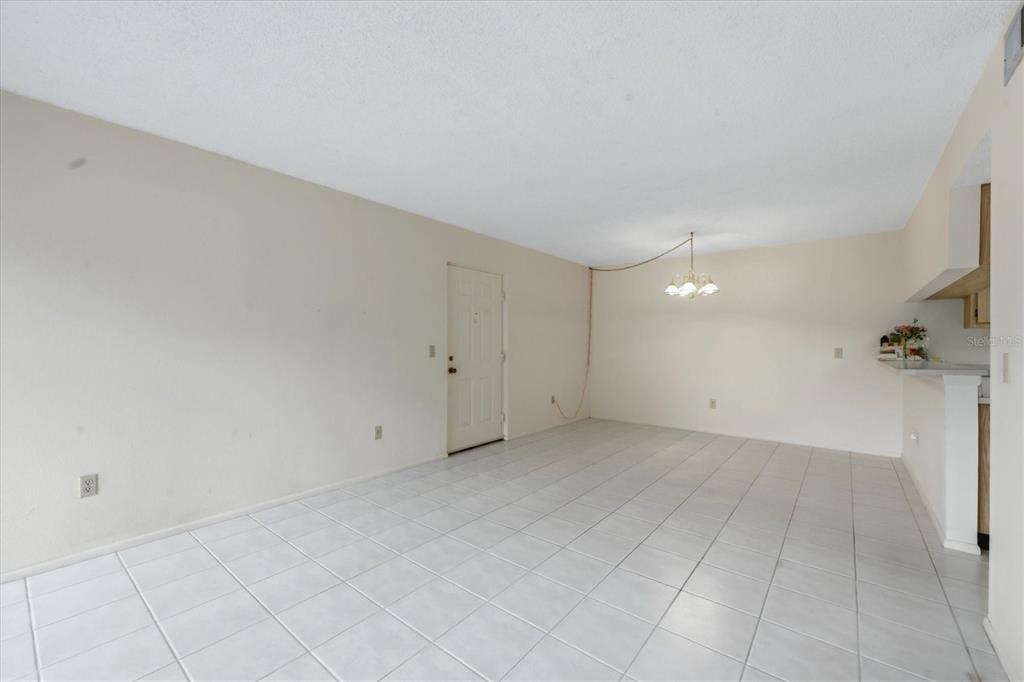 An empty room with white tile flooring, a white door, and a hanging light fixture — 1515 FORREST NELSON BOULEVARD UNIT C105, PORT CHARLOTTE, FL