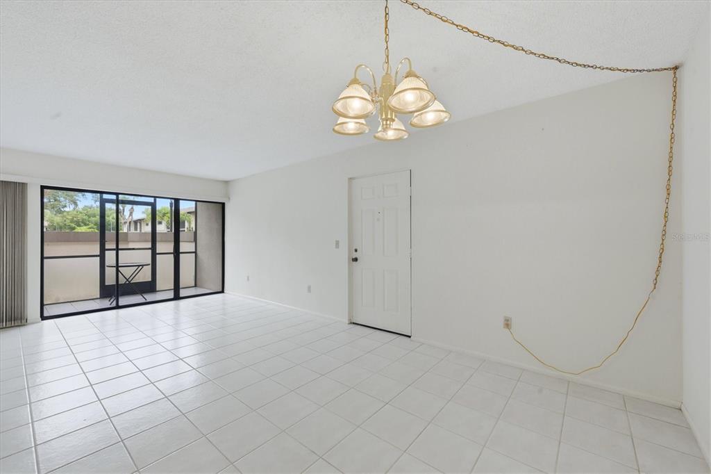 A bright room with white tile floors, a chandelier, and a sliding glass door — 1515 FORREST NELSON BOULEVARD UNIT C105, PORT CHARLOTTE, FL
