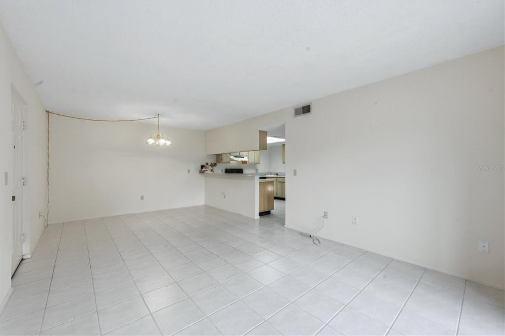 An open-concept dining and living area features white tile flooring and a kitchen pass-through window — 1515 FORREST NELSON BOULEVARD UNIT C105, PORT CHARLOTTE, FL