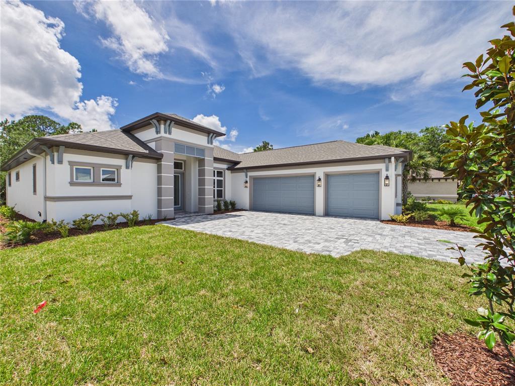 A single-story house with a white stucco facade, gray trim, and a two-car garage — 230 S RIVERWALK DRIVE, PALM COAST, FL
