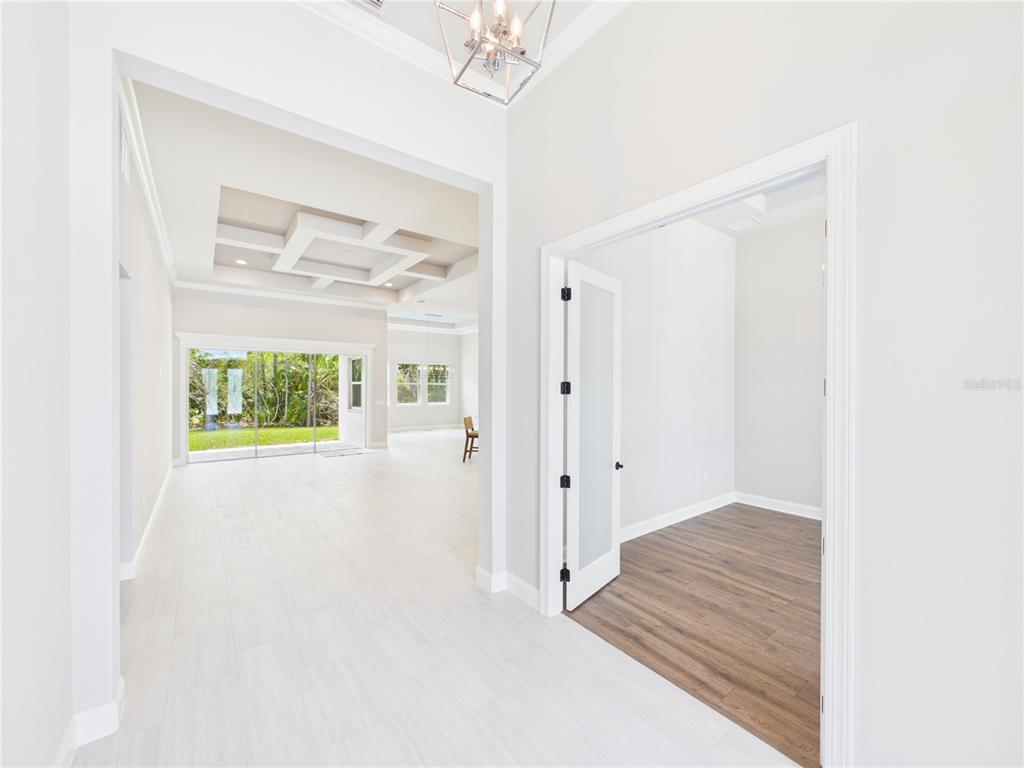 A bright entryway leads to a living area with a coffered ceiling and sliding glass doors — 230 S RIVERWALK DRIVE, PALM COAST, FL