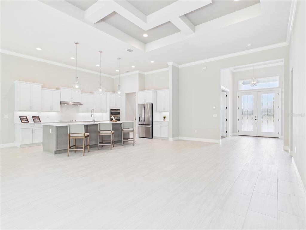 A modern, open-concept kitchen features white cabinetry, a large island with seating, and tile flooring — 230 S RIVERWALK DRIVE, PALM COAST, FL