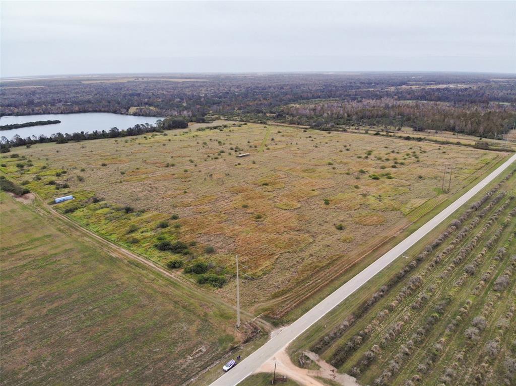 An aerial view shows a large, grassy, undeveloped lot bordered by a road and trees — OLD BOWLING GREEN ROAD, FORT MEADE, FL
