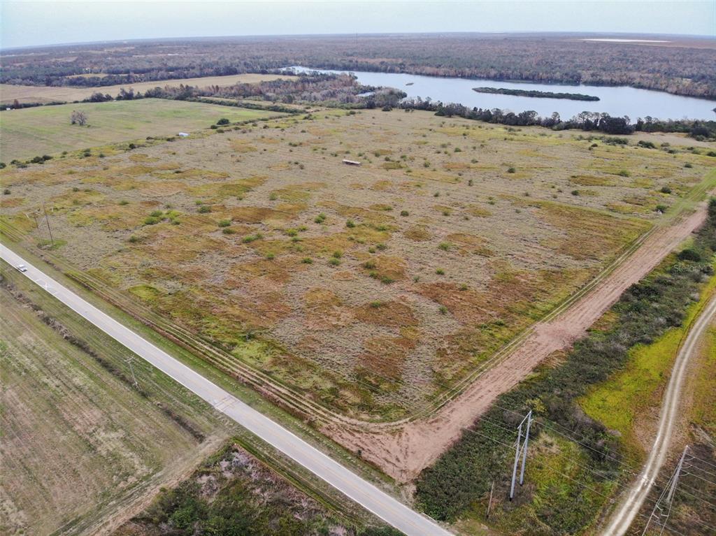 An aerial view shows a large, flat, grassy field bordered by a road and a lake — OLD BOWLING GREEN ROAD, FORT MEADE, FL