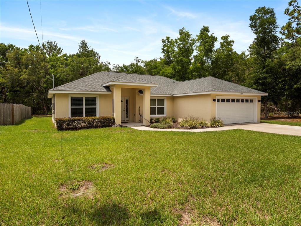 A single-story house with a yellow stucco exterior, gray shingled roof, and a two-car garage — 9432 SE 159TH LANE, SUMMERFIELD, FL