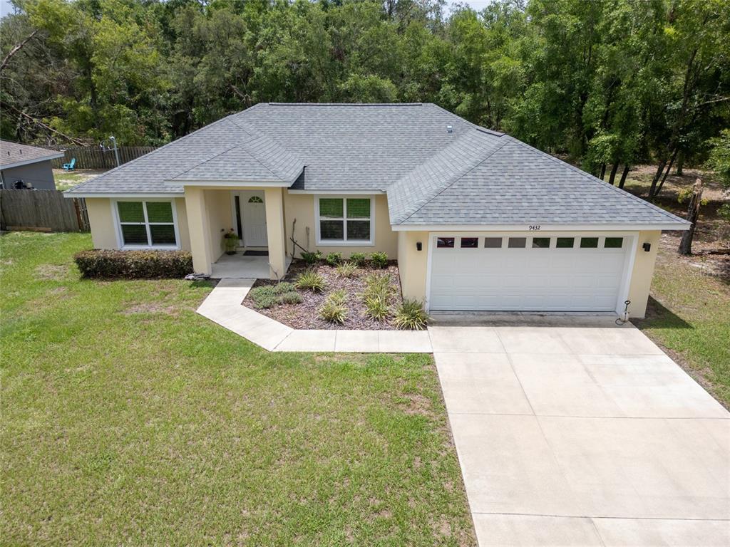 A single-story house with a light-colored exterior, a gray shingled roof, and a two-car garage — 9432 SE 159TH LANE, SUMMERFIELD, FL