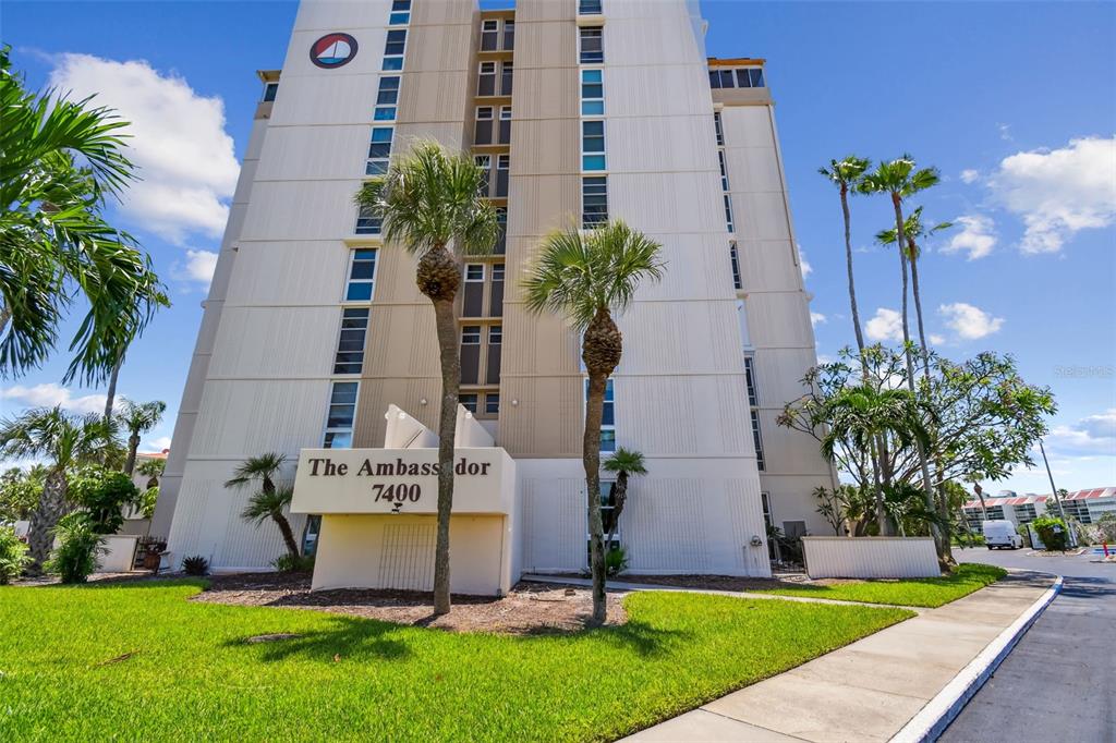 A tall, beige residential building with palm trees in front under a blue sky — 7400 SUN ISLAND DRIVE S UNIT 411, SOUTH PASADENA, FL