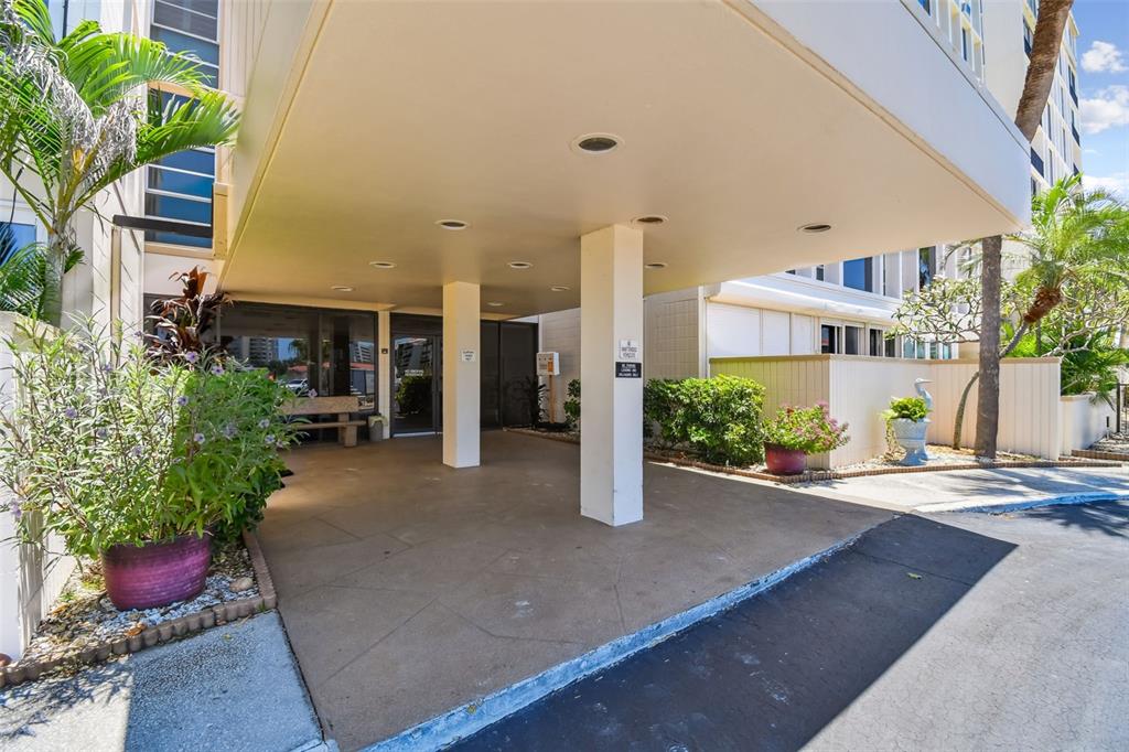 The exterior of a building features a covered entrance with concrete pillars and potted plants — 7400 SUN ISLAND DRIVE S UNIT 411, SOUTH PASADENA, FL