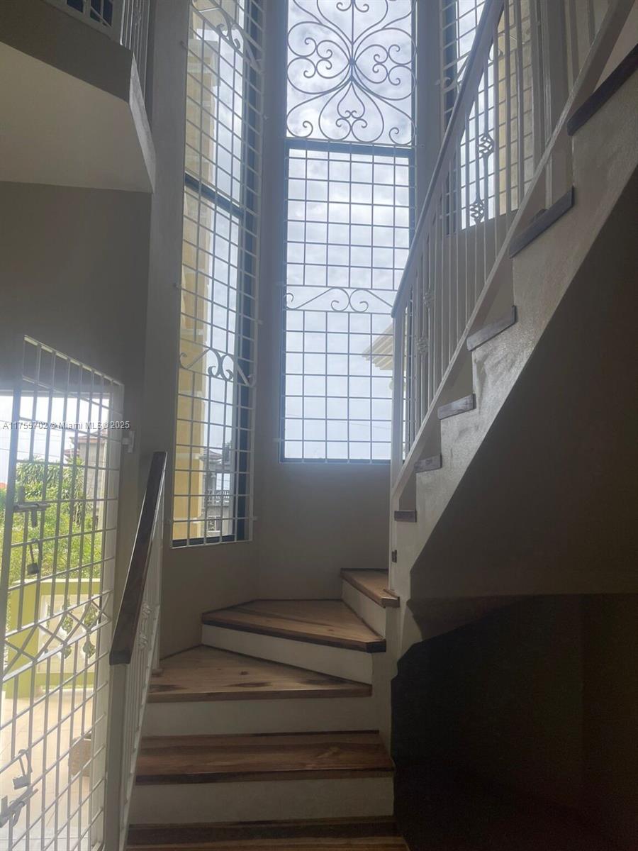 A staircase with wooden treads ascends past a tall window featuring decorative metal security grilles — 00 Discovery Pointe, Discovery Bay, St Ann, Jamaica, NA, NA