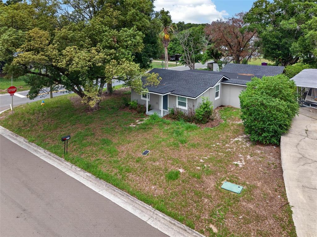 An elevated exterior view of a single-story gray house with a dark shingled roof — 305 S SHARP STREET, LAKE WALES, FL