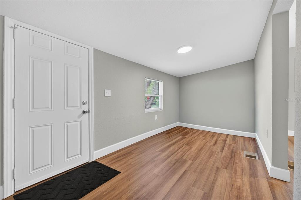 An empty room with light gray walls, wood-look flooring, a white front door, and window — 305 S SHARP STREET, LAKE WALES, FL