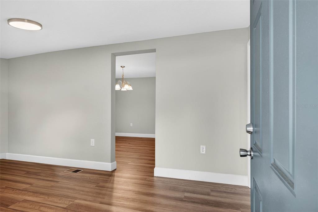 A view from a doorway into a living room with wood-look flooring and light walls — 305 S SHARP STREET, LAKE WALES, FL
