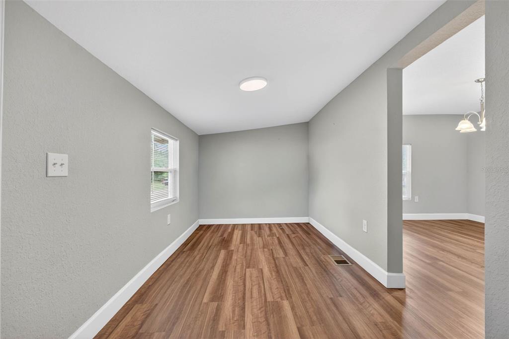 An empty room with light gray walls, wood-look flooring, and a window — 305 S SHARP STREET, LAKE WALES, FL