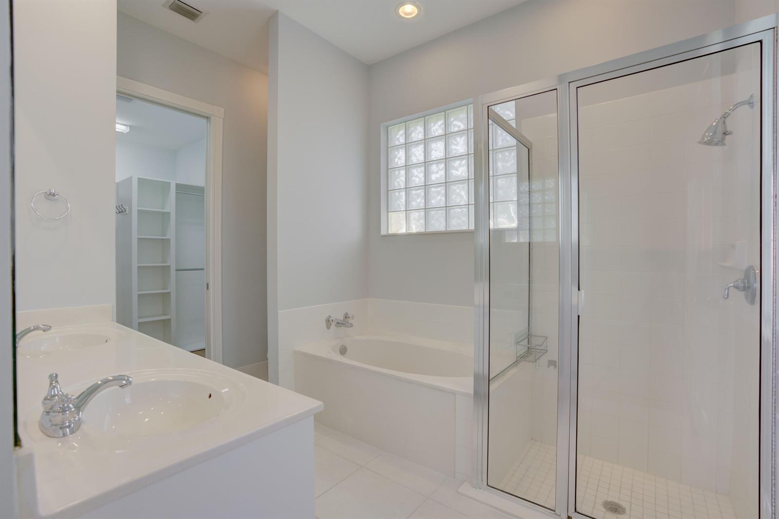 A bathroom features a double vanity, a soaking tub, and a glass-enclosed shower — 256 San Remo Drive, Jupiter FL 33458, JUPITER, FL