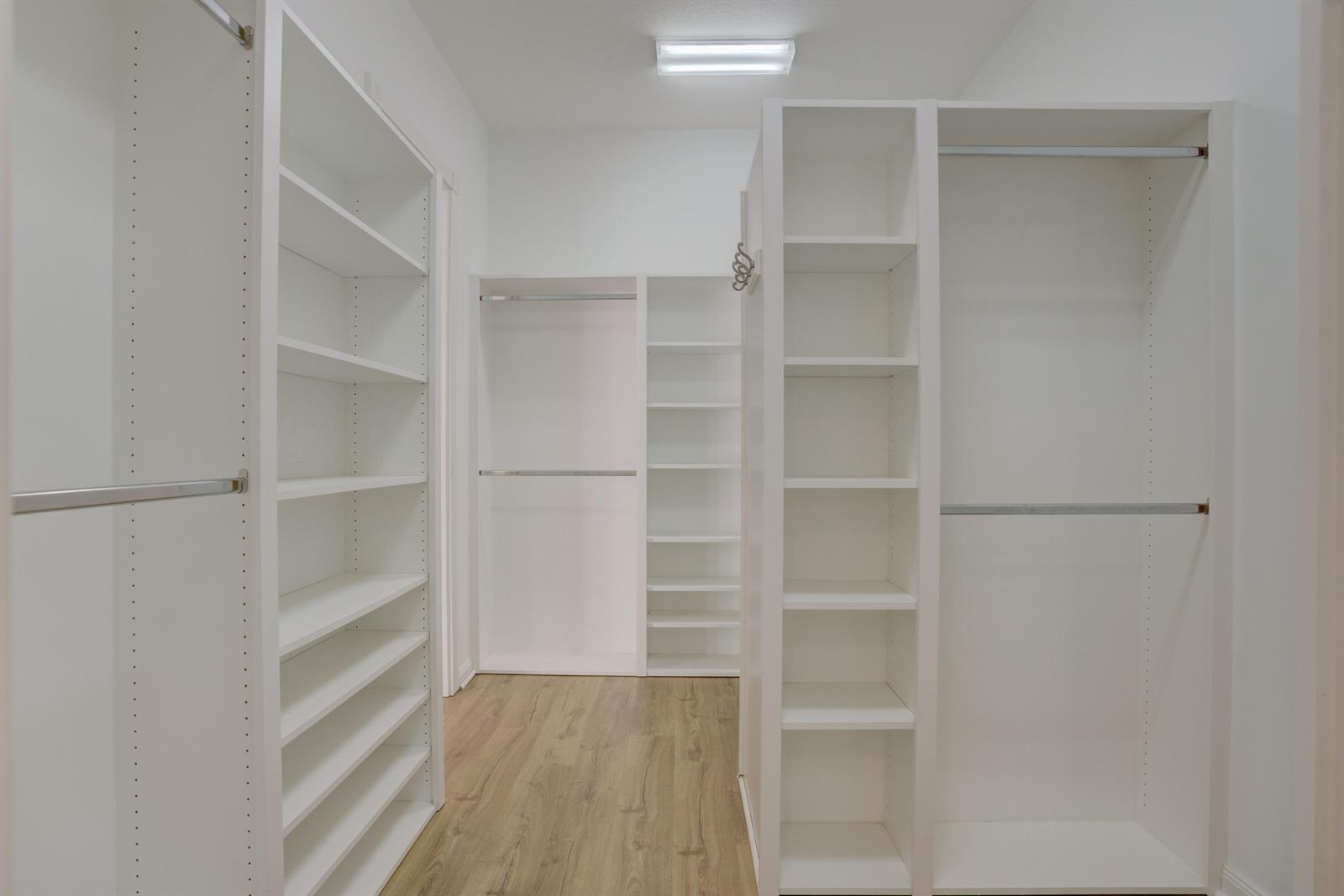 A walk-in closet features white shelving units, hanging rods, and light wood-look flooring — 256 San Remo Drive, Jupiter FL 33458, JUPITER, FL