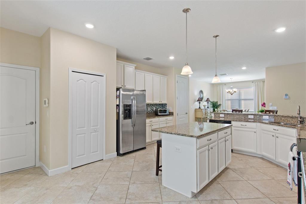 A kitchen features white cabinetry, granite countertops, a center island, and stainless steel appliances — 1311 GLENEAGLES LANE, DAVENPORT, FL