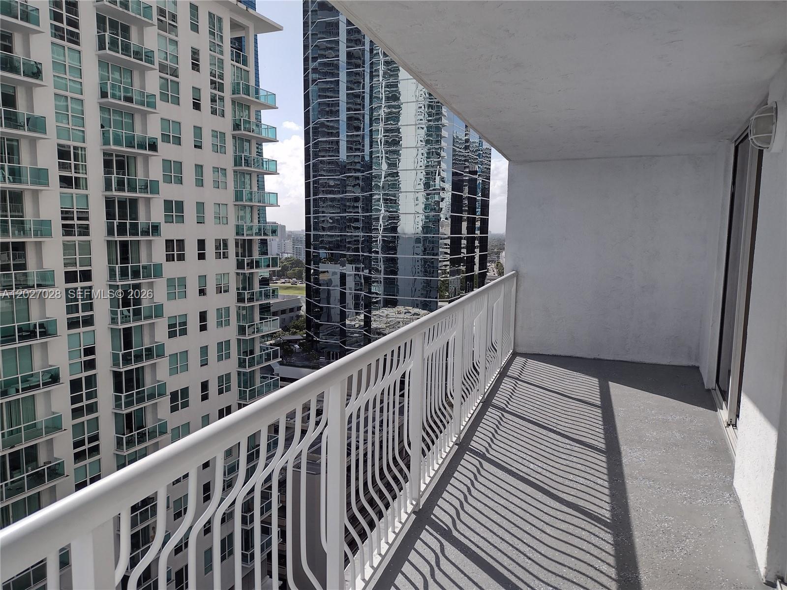 A balcony with a white metal railing overlooks a high-rise building and city skyline — 1200 Brickell Bay Dr # 2005, Miami FL 33131, MIAMI, FL