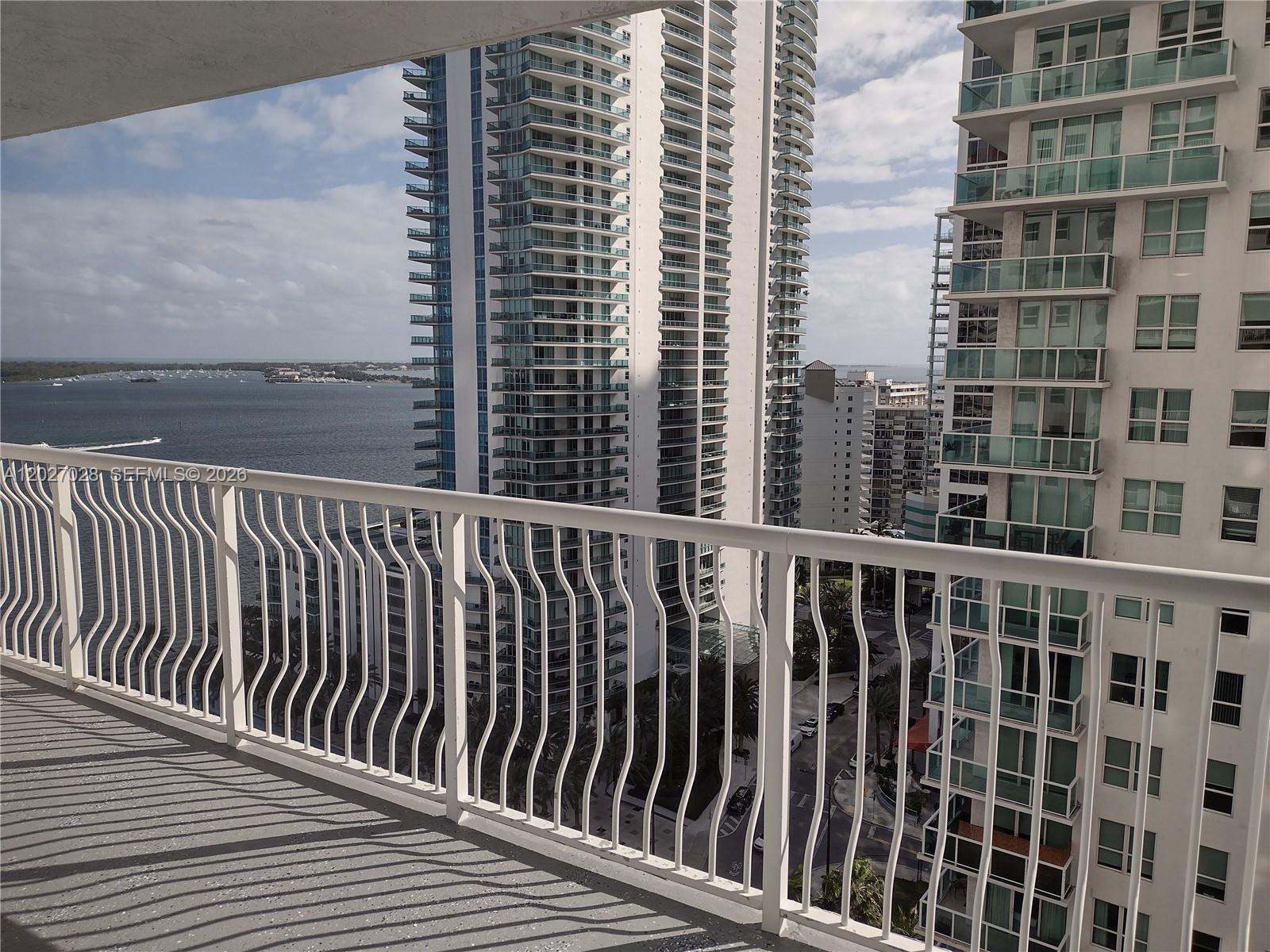 A balcony with a white metal railing overlooks a bay and tall residential buildings — 1200 Brickell Bay Dr # 2005, Miami FL 33131, MIAMI, FL